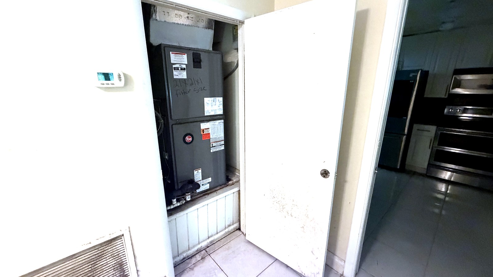 Armário aberto no corredor de uma casa na Flórida, mostrando um aparelho de tratamento de ar com manchas de mofo após um vazamento no telhado